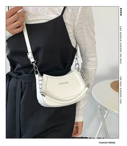 Detailansicht der weißen Halbmond-Tasche mit Goldlogo und elegantem Kettenriemen