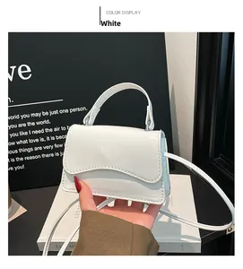 Détail du sac à main en cuir verni blanc avec rabat ondulé et ornements argentés
