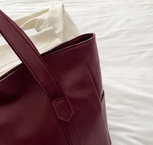 Detailaufnahme der Nähte am Griff der burgunderroten Shopper-Tasche aus PU-Leder