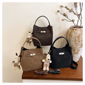 Drei minimalistische Wildleder-Eimertaschen in Braun und Schwarz mit Plüschanhänger