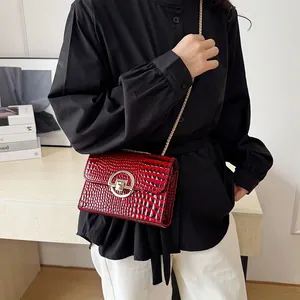 Fashionable red crocodile pattern crossbody bag with gold chain strap on female model