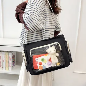 Black ita bag with transparent window, plush bear, and adjustable white strap for school