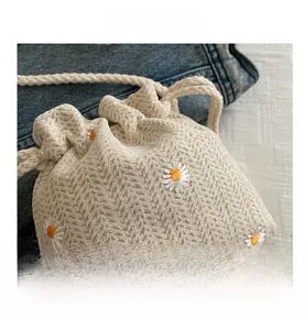 Detail view of woven drawstring bucket bag with embroidered daisy floral pattern