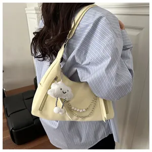 Detail of light yellow shoulder bag with plush cloud charm and pearl chain accent