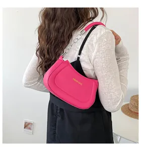 Modell mit einer rosa halbmondförmigen Umhängetasche mit Silberkette und Golddruck