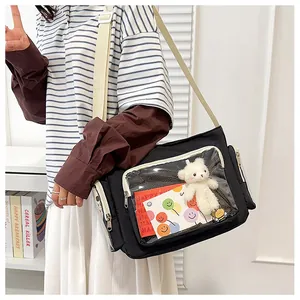 Detail of black canvas crossbody bag with clear PVC window and plush bear charm