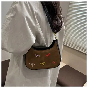 Détail du sac bandoulière en daim marron avec broderies de nœuds colorés et or
