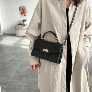 Chic black woven texture crossbody bag with gold clasp shown on a model