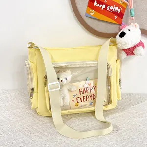Close-up of yellow ita bag featuring a transparent PVC window and a white teddy bear inside
