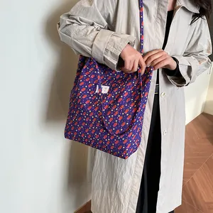 Sac fourre-tout en toile violette à fleurs et pois rouges avec étiquette sur un mannequin