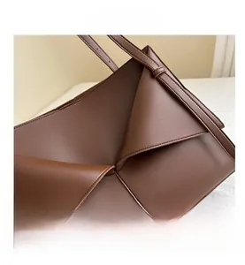 Détail du sac cabas en cuir marron montrant le pli géométrique et la bandoulière réglable
