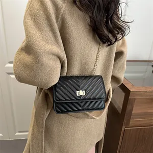 Chic black chevron quilted leather handbag with gold chain strap shown on a model