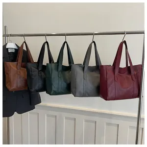 Minimalistische Leder-Tragetaschen in fünf Farben, hängend an einem Metallregal