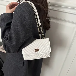 Minimalist white quilted shoulder bag with gold hardware shown on a female model