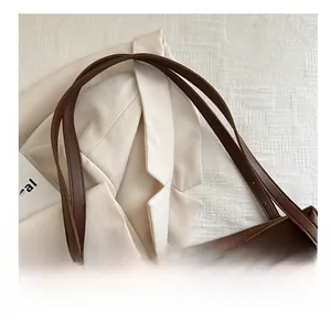 Détail montrant la bandoulière en cuir marron et la texture de ce sac cabas