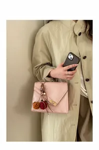 Detail of pink fashion handbag with golden twist lock and plush charm on trench coat