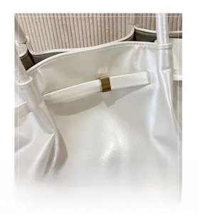 Dettaglio della fibbia dorata e della pelle perla testurizzata su borsa a secchiello chic