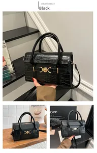 Detail view of black crocodile pattern handbag featuring a round gold buckle and dual straps