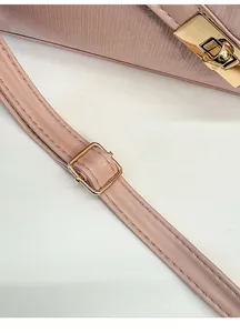 Close-up of pink textured leather shoulder strap with adjustable gold buckle and hardware