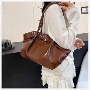 Borsa tote plissettata marrone lucido che mostra la trama drappeggiata sul modello