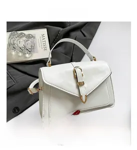 Detail of white leather handbag showing envelope flap and golden V-shaped metal buckle