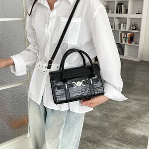 Elegant black crocodile pattern handbag with metal buckle worn by model in a bright room
