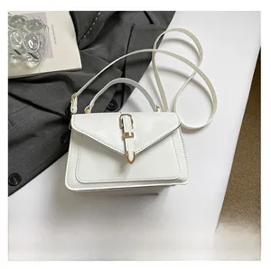 Detail of white leather handbag with gold buckle and smartphone for size reference