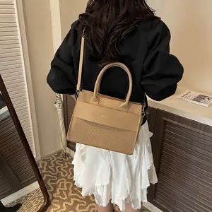 Detail of beige faux crocodile tote bag with smooth leather strap and gold logo