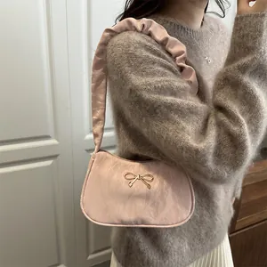 Sac à bandoulière rose avec lanière à volants et nœud doré sur tissu texturé