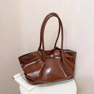 Sac seau en cuir verni marron brillant avec boucle dorée sur présentoir blanc
