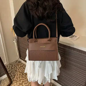 Detailed view of brown crocodile-embossed leather tote bag showing texture and handle