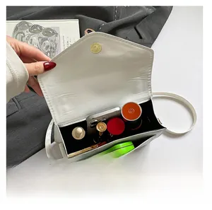 Internal view of a white leather crossbody bag showing compartments for phone and cosmetics