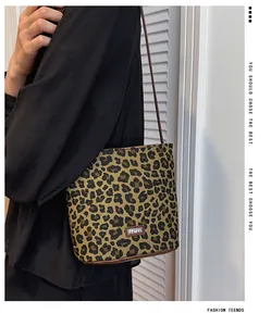 Macro shot of stylish leopard print canvas bucket bag with leather logo and shoulder strap