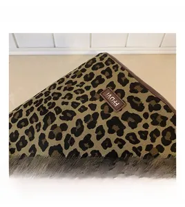 Detail shot of leopard print canvas bucket bag with brown leather label and trim