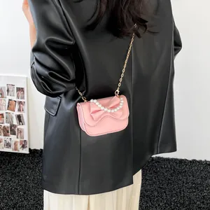 Pink mini crossbody bag with leather texture and 3D bow detail featuring a pearl handle