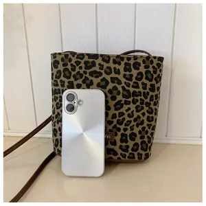 Detailed view of leopard print bucket bag next to a smartphone for size comparison
