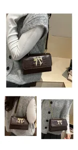 Detail of dark brown faux crocodile skin texture and gold butterfly clasp on handbag