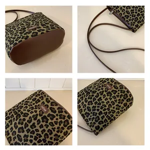 Detail view of leopard print bucket bag showing leather base and zipper closure