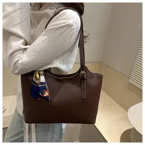 Detail of dark brown minimalist tote bag with wave-shaped rim and decorative silk scarf