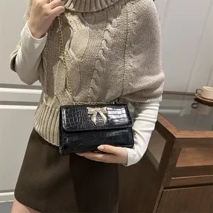 Elegant black crocodile pattern crossbody bag with a gold butterfly buckle for women