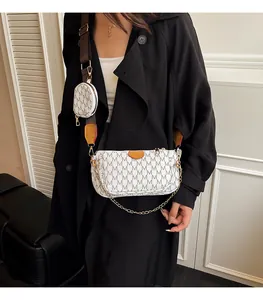 Detail of white crossbody bag with M-pattern print, gold chain, and round coin purse