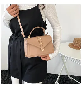 Detail shot of beige leather crossbody bag featuring a gold U-shaped metal lock and strap