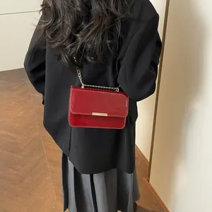 Chic red patent leather crossbody bag with gold chain strap on professional model