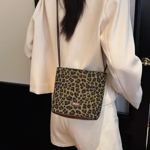Fashionable leopard print bucket bag with brown leather straps shown on a model