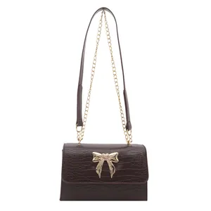 Dark brown faux crocodile leather crossbody bag with a large golden butterfly bow ornament