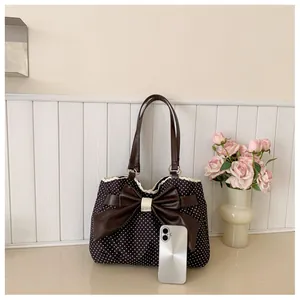 Detailed view of polka dot tote bag featuring a large leather bow and lace trim