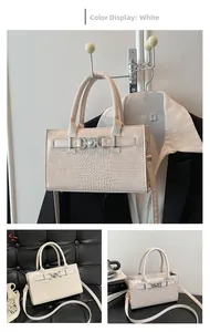 Detail of white crocodile pattern handbag featuring a heart-shaped metal buckle and dual handles