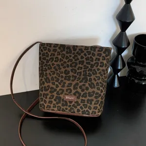 Close-up of leopard print bucket bag with leather logo tag and brown strap detail
