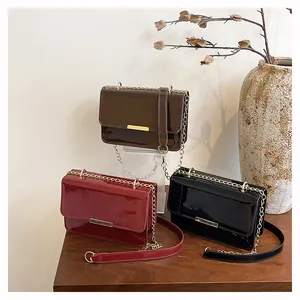 Detail view of stylish shiny patent leather crossbody bags with golden metal buckles