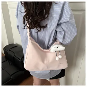 Detail of light pink half-moon shoulder bag featuring a cute white cloud plush charm